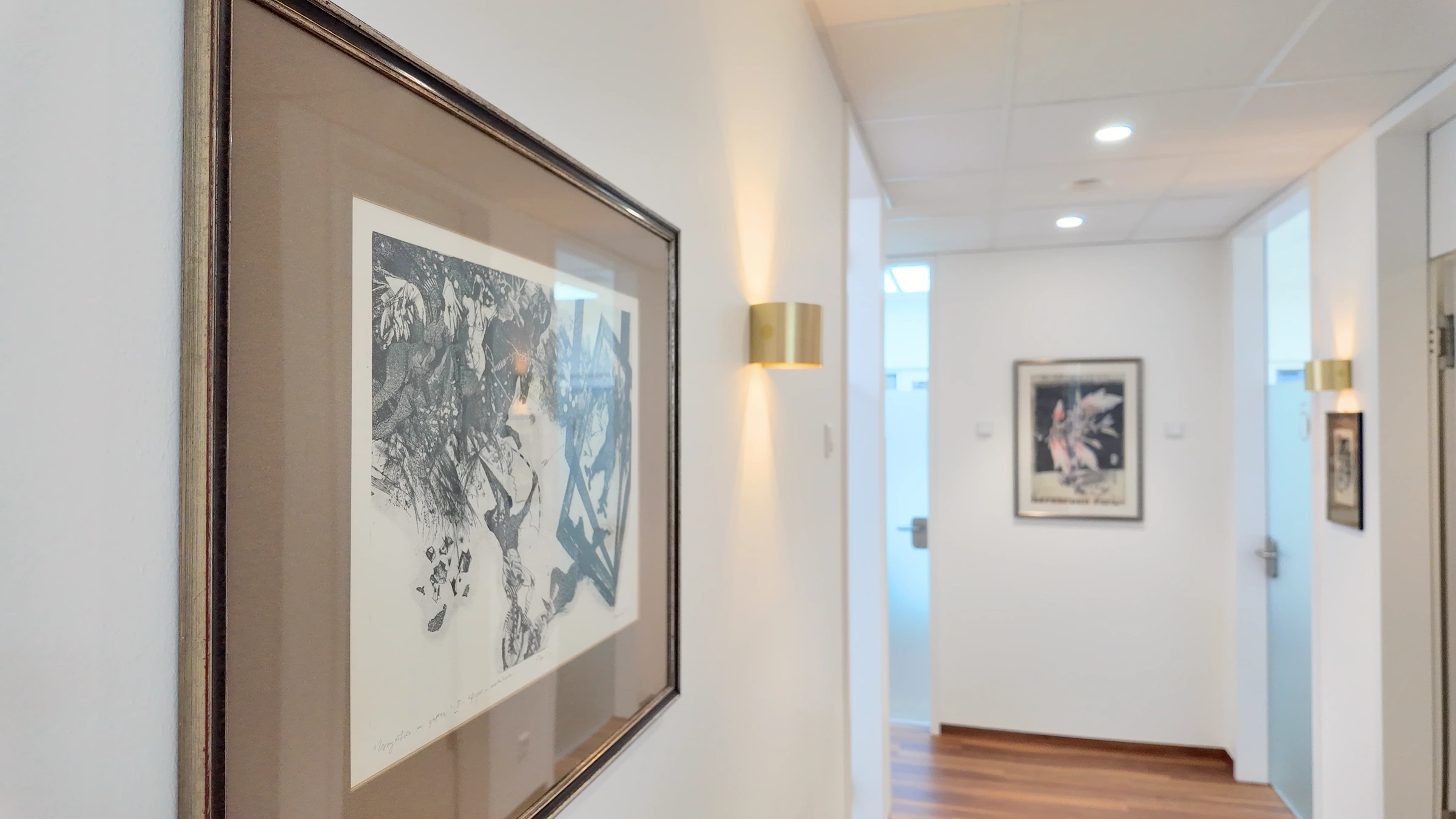 Gerahmte Kunst und goldene Wandleuchten im Praxisflur